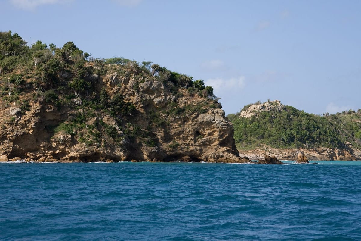 Garis pantai berbatu dan laut biru di Antigua