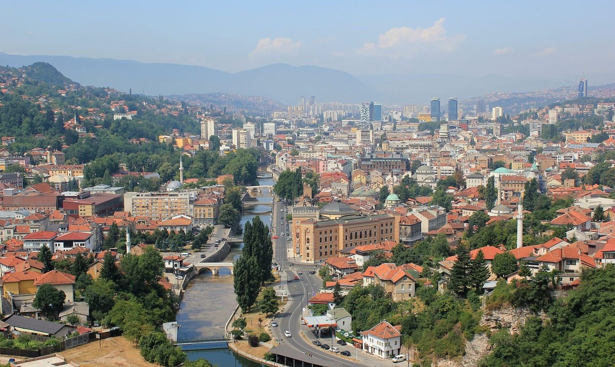 Atap rumah dan menara masjid di cekungan kota Sarajevo
