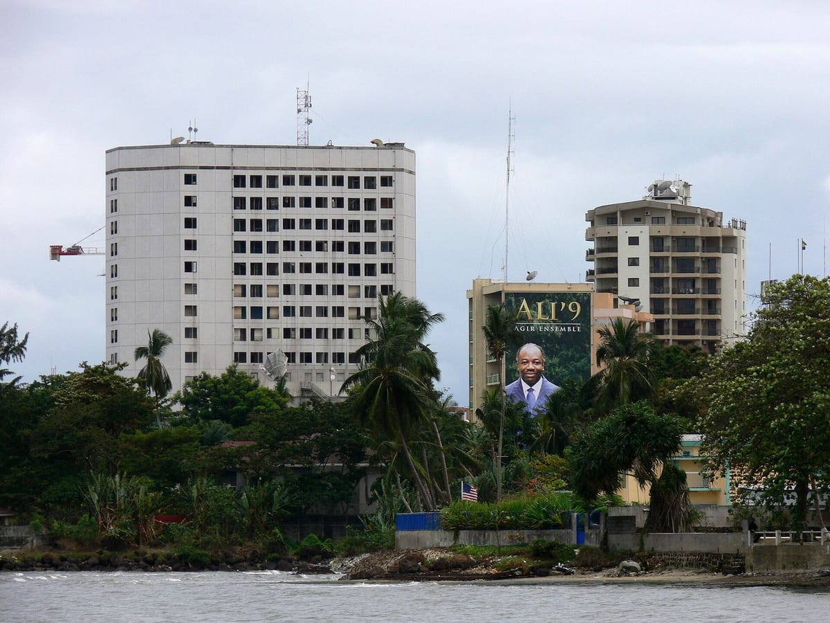 Pantai di tepi Libreville dengan pohon kelapa dan laut